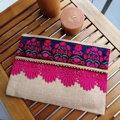 a pink and blue purse sitting on top of a wooden table next to a candle