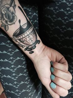 a person with a tattoo on their arm holding a coffee cup and saucer in her hand