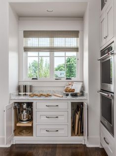 a kitchen with white cabinets and wooden floors