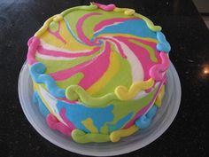 a colorful cake sitting on top of a table covered in frosting and icing