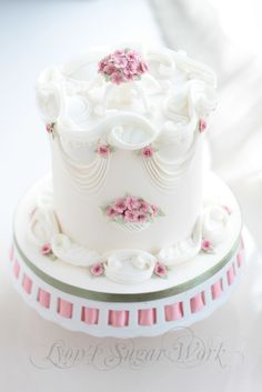 there is a white cake with pink flowers on the top and bottom, sitting on a plate