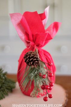 a red bag with pine cones and berries tied to it sitting on a wooden table