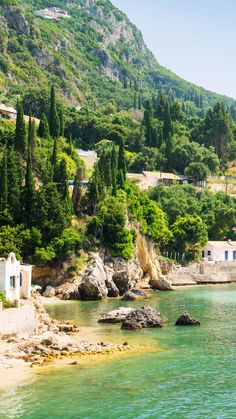 the water is crystal blue and clear with green trees around it, along with some houses