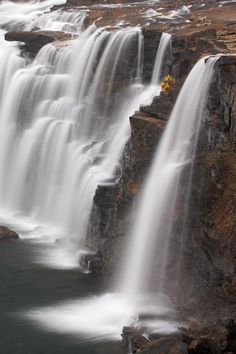 the waterfall is very tall and has lots of water running down it's sides