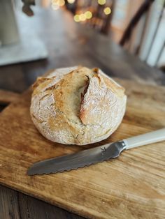 a loaf of bread sitting on top of a wooden cutting board next to a knife