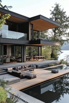 an outdoor living area with couches and tables next to the water