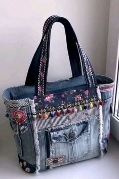 a handbag made out of old jeans is sitting on the window sill in front of a window