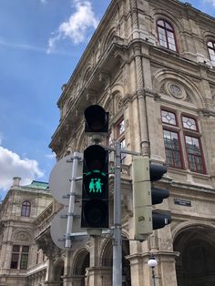 a traffic light in front of an old building with a green pedestrian signal on it