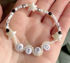 a hand holding a beaded bracelet with letters and stars