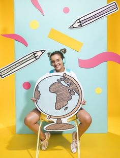 a woman sitting on a chair holding up a sign with the earth drawn on it