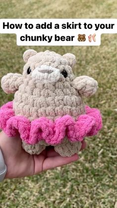 a hand holding a crocheted stuffed animal with pink ruffles on it