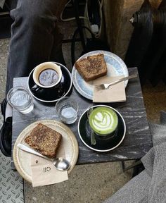 two plates with slices of cake on them and cups of coffee in front of them