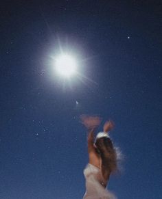 a woman flying through the air while riding a snowboard under a moon lit sky