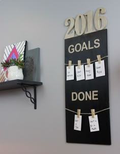 a black and white sign hanging on the side of a wall next to a potted plant