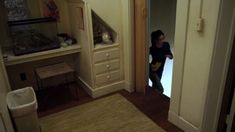 a young child standing in front of an open door to a room with a fish tank on the wall