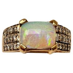 This stunning 14k yellow gold ring showcases a beautiful approx. 8mm x 10.5mm vibrant rectangle-shaped opal and 24 side diamonds set in a rectangular frame. The vibrant colour of the opal is sure to catch the eye, and the 24 diamonds add an extra touch of elegance to this piece. The ring is a size 10.25 and crafted with high-quality materials, making it a durable and long-lasting addition to any jewellery collection. The secondary diamond adds an additional sparkle to the ring, making it perfect Formal Multi-stone Rectangular Ring, Elegant Multi-stone Rectangular Rings, Elegant Rectangular Multi-stone Rings, Modern Multi-stone Rectangular Jewelry, Gold Multi-stone Rectangular Ring, Gold Rectangular Multi-stone Jewelry, Elegant Rectangular Opal Ring, Rectangular Yellow Gold Ring With Gemstone, Opal Diamond Ring