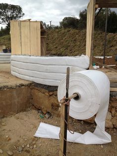 two rolls of white toilet paper sitting on top of a pile of dirt next to a building