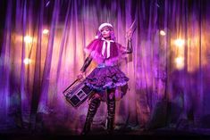 a woman is dressed in purple and holding a suitcase