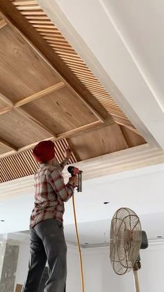 a man is working on the ceiling in his room with a fan and air conditioner