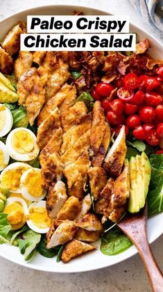 a white bowl filled with chicken, hard boiled eggs and cherry tomatoes on top of lettuce