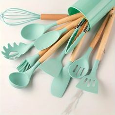 green kitchen utensils lined up on a white surface