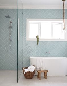 the bathroom is decorated in blue and white with herringbone tile on the walls, along with a claw foot tub