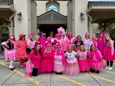 a group of women in pink dresses and tutus posing for a photo at the front of a building