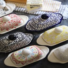 several decorative ceramic dishes are on the table with different colors and designs, including black, white, yellow, red, blue