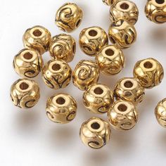 many gold colored beads on a white surface with one bead in the middle and two holes at the bottom