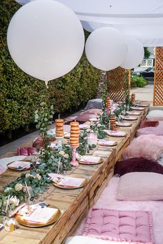 a long table is set up with balloons and plates