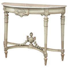 an ornate console table with marble top and carved details on the legs, in white