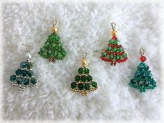 four christmas tree beaded charms sitting on a white surface