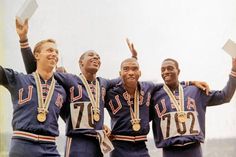 three men in blue uniforms are holding up their hands and smiling at the camera with medals around their necks