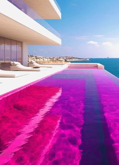 an outdoor swimming pool with pink water and lounge chairs overlooking the ocean in front of a high rise building