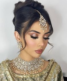 a woman wearing an elaborate necklace and matching headpiece with her hair in a bun