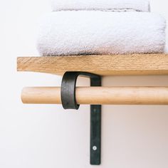 two white towels are sitting on top of a wooden shelf next to a towel rack