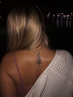 the back of a woman's neck with a small pine tree tattoo on it