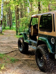 a green and tan jeep parked in the woods