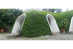 three white sculptures with plants growing out of them in the middle of a gravel area