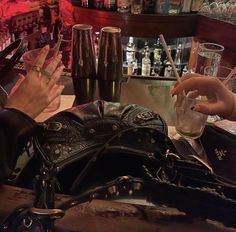 two women sitting at a bar with their hands on the purses and drinks in front of them