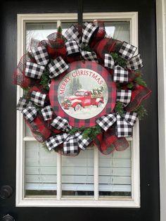 a christmas wreath on the front door of a house with red and black plaid ribbon