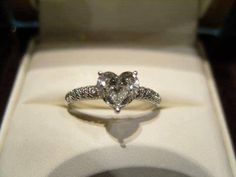 a heart shaped diamond ring sitting on top of a white box