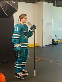 a hockey player is holding a microphone and standing in front of an umbrella on the floor