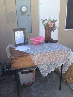 a table with a cowboy boot on it next to a pink bowl and some hay