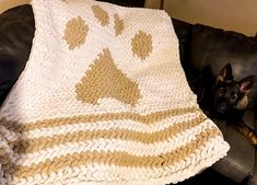 a black dog laying on top of a couch next to a white and brown blanket