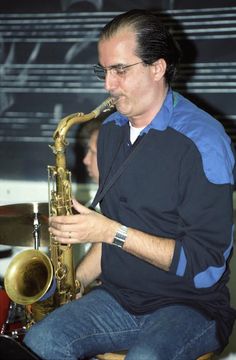 a man sitting on a stool playing a saxophone