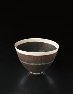 a black and white bowl sitting on top of a dark surface with light coming from it