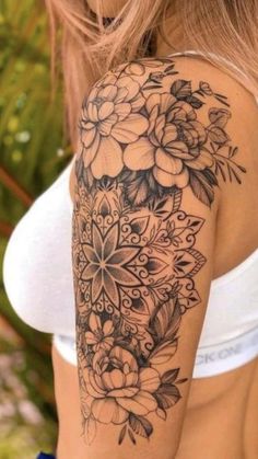 a woman's arm with flowers and leaves tattooed on the back of her shoulder