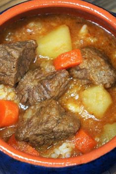 a white plate topped with meat and carrots covered in gravy on top of a wooden table