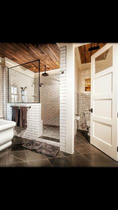 a bathroom with white brick walls and black tile flooring, along with a walk in shower